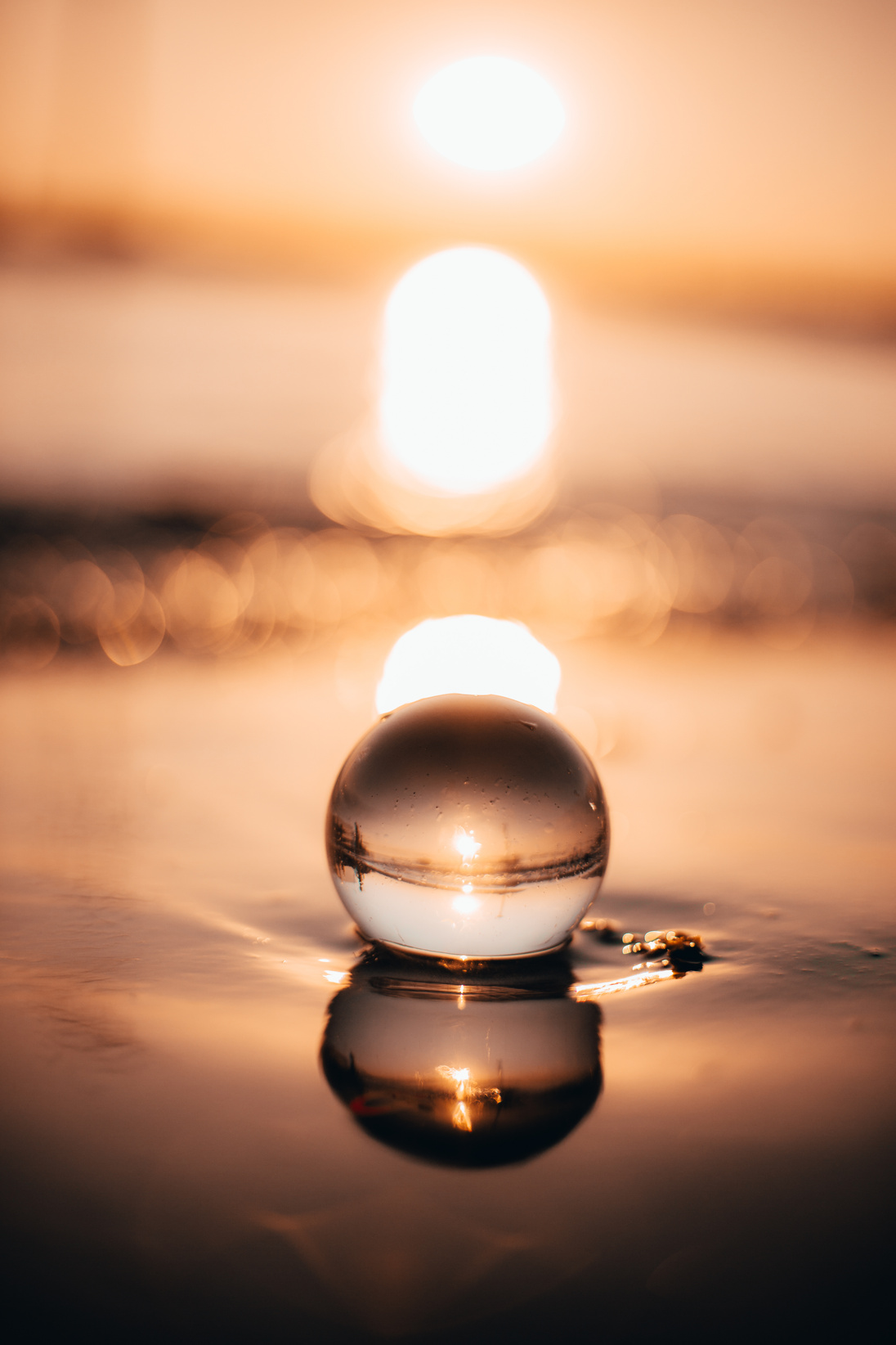 Glass ball on calm lake water surface in evening